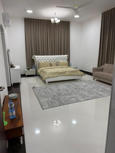 a bedroom with a bed and a couch and a table at فيلا للايجار دورين في عوقد الشمالية in Salalah