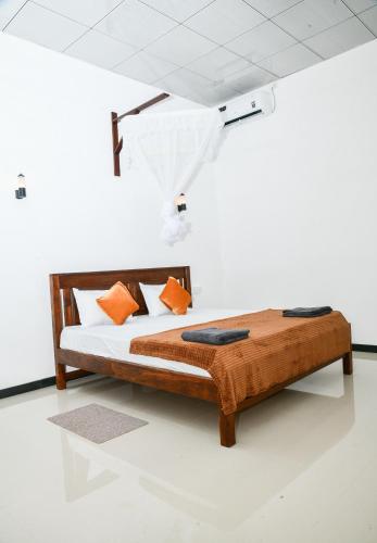 a wooden bed with orange pillows in a room at EverGreen Resort Udawalawe in Udawalawe