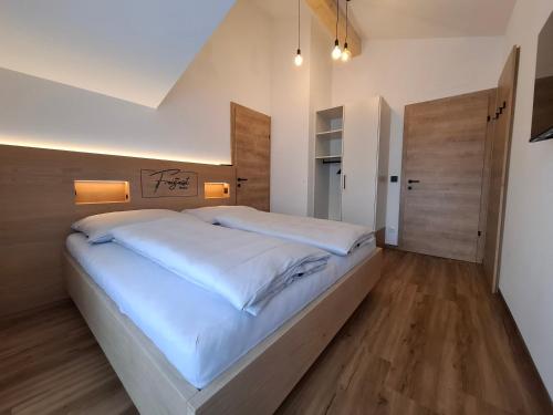 una camera da letto con un grande letto bianco e pavimenti in legno di Das Freigeist a Flachau