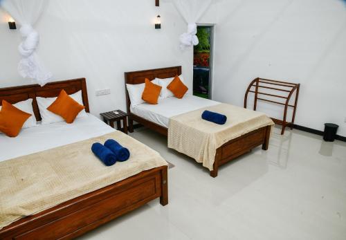 two beds with blue pillows in a room at EverGreen Resort Udawalawe in Udawalawe