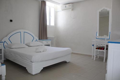 a bedroom with a white bed and a mirror at Hôtel Medina in Sousse