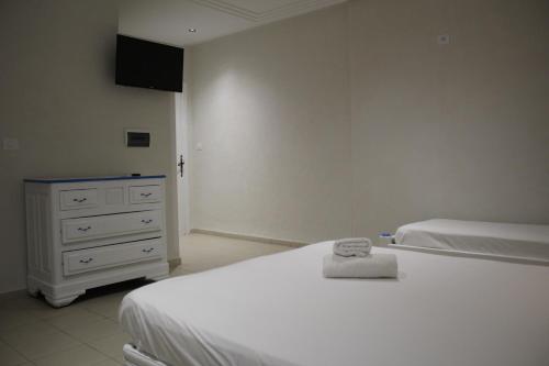 a bedroom with two white beds and a dresser at Hôtel Medina in Sousse