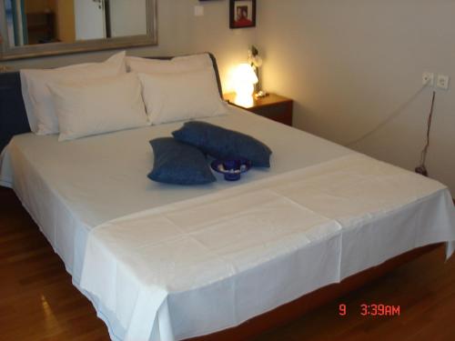 a large white bed with two blue pillows on it at RELAX WITH SEA VIEW No 1!!!! in Varkiza
