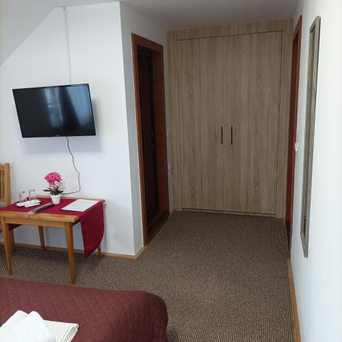 una stanza con una tv, un tavolo e una porta di Casa OALPEM a Rîşnov
