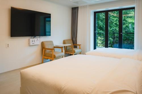 a hotel room with two beds and a flat screen tv at Seorak Hotel Misong in Yangyang