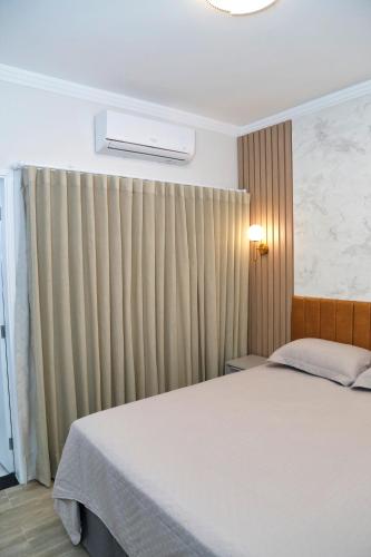 a bedroom with a bed and a window with curtains at Comforto e tranquilidade in Franca