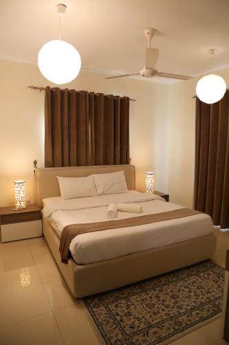 a bedroom with a large bed with two lights at Royal Suites Muscat in Ma‘ābīlah