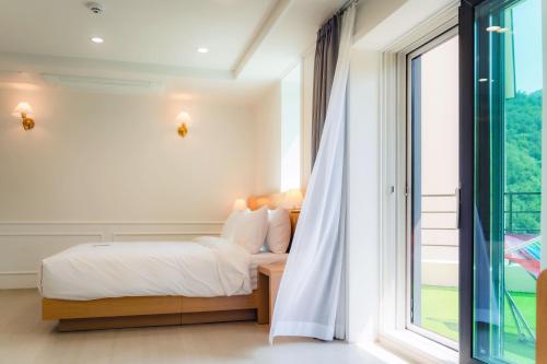 a bedroom with a bed and a large window at Seorak Hotel Misong in Yangyang