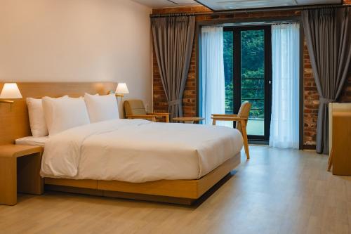 a bedroom with a large bed and a large window at Seorak Hotel Misong in Yangyang