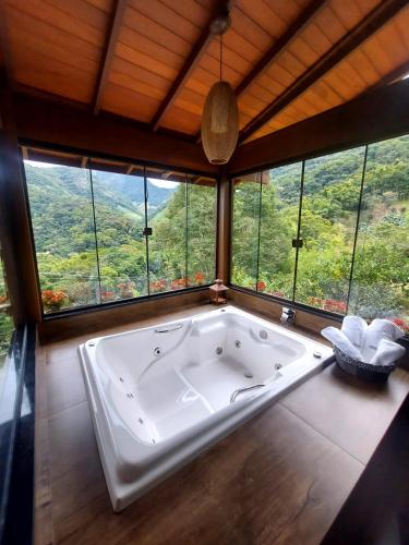 a large bath tub in a room with windows at Recanto Lua de Lumiar in Nova Friburgo