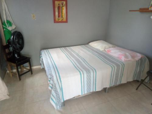a small bed in a room with a chair at kitnet - Studio de Hóspedes da Menina Maricotinha in Manaus