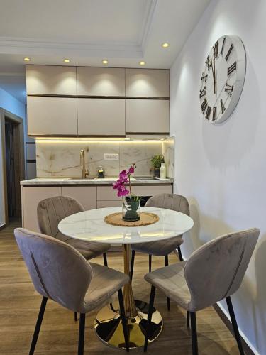 a kitchen with a table and chairs and a clock at Apartmani Nikic -Tivat in Tivat