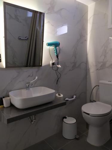 a bathroom with a sink and a toilet and a mirror at Tennis Home-Pozar, Piperia! in Áno Rodoniá