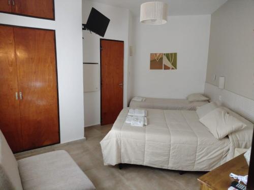 a bedroom with two beds and a tv in it at Hotel Alumine in Villa Cura Brochero