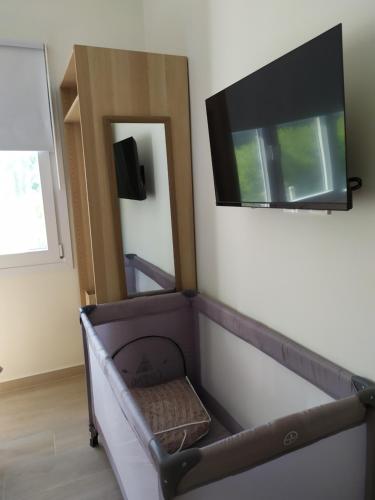 a living room with a tv on the wall and a chair at Tennis Home-Pozar, Piperia! in Áno Rodoniá