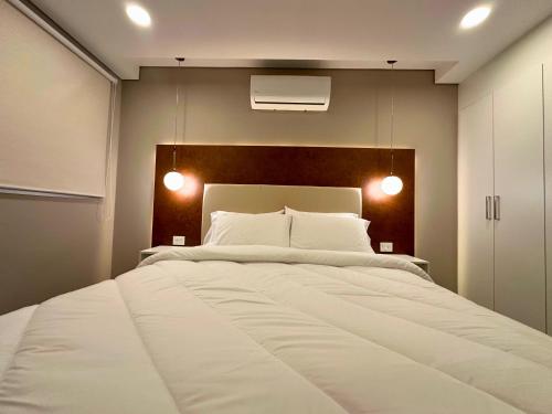 a bedroom with a large white bed with two lights at ABIBA Apart-Hotel & SPA in Asuncion