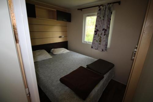 ein kleines Schlafzimmer mit einem Bett und einem Fenster in der Unterkunft Land's Hause Bungalows par La Conciergerie Française Emplacement S5 in Pataias