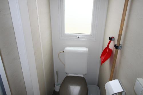 ein kleines Bad mit einem WC und einem Fenster in der Unterkunft Land's Hause Bungalows par La Conciergerie Française Emplacement S6 in Pataias