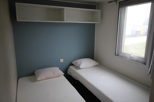 zwei Betten in einem kleinen Zimmer mit Fenster in der Unterkunft Land's Hause Bungalows par La Conciergerie Française Emplacement S6 in Pataias