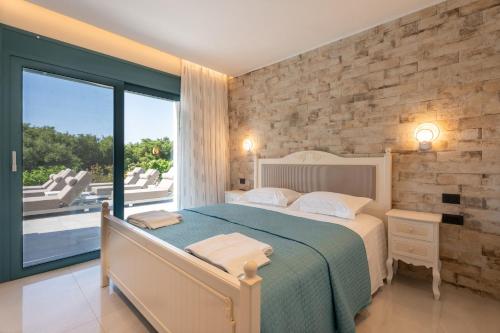 a bedroom with a bed and a large window at Villa Prestige Karavados in Karavadhos