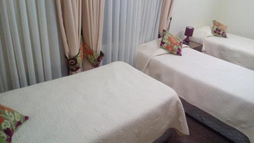 a room with two beds with white sheets at Hotel Le Mirage in Puerto Montt