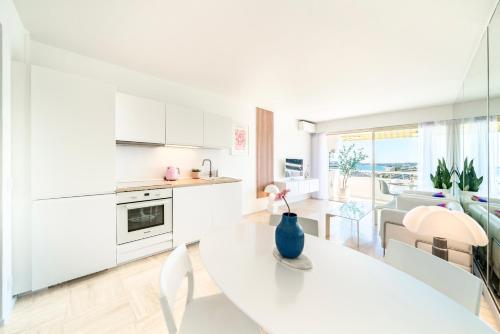 une cuisine blanche avec une table et des chaises blanches dans l'établissement T3 luxe Marina Baie des Anges vue mer panoramique, à Villeneuve-Loubet