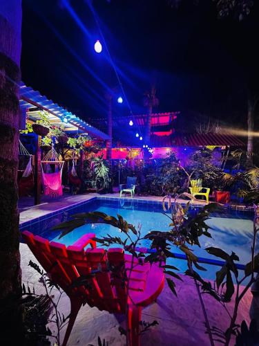 a swimming pool at night with pink chairs and lights at Hostal Hilltop Salento in Salento