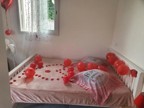 a room with a bed with red balloons on it at Bungalow vacances in Sainte-Rose