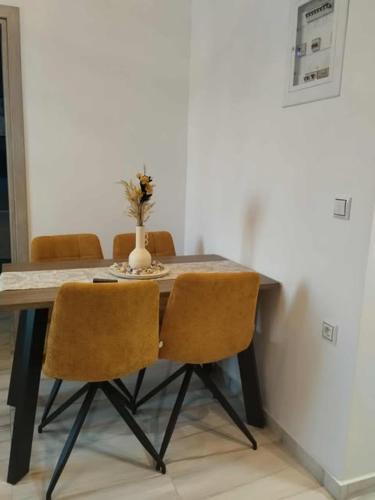 a dining room table with three chairs and a vase on it at Thanos Cozy Apartments in Skala Kallonis