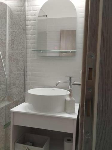 a white bathroom with a sink and a mirror at Thanos Cozy Apartments in Skala Kallonis