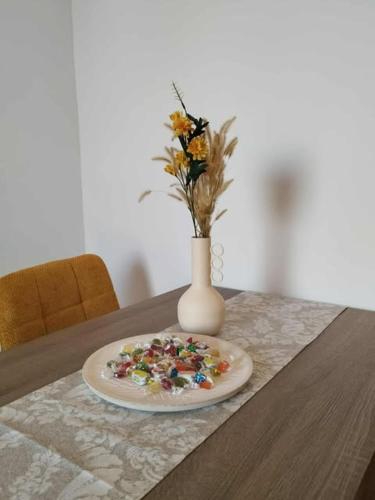 a plate on a table with a vase with flowers at Thanos Cozy Apartments in Skala Kallonis