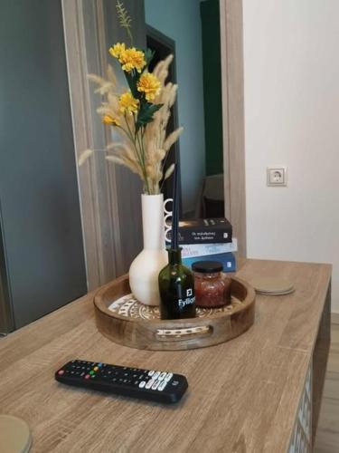 a table with a vase with flowers and a remote control at Thanos Cozy Apartments in Skala Kallonis