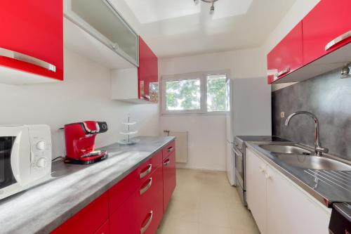 a kitchen with red cabinets and a sink at Appartement vue sur Lac proche métro in Créteil