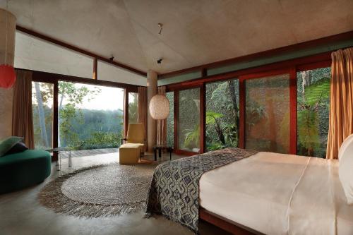 1 dormitorio con 1 cama grande y ventanas grandes en Umah Tampih Luxury Private Villa - CHSE Certified, en Ubud