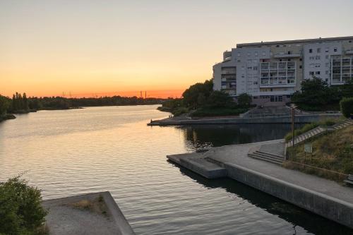 a view of a river at sunset with buildings at Appartement vue sur Lac proche métro in Créteil