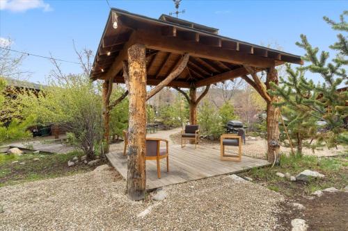 a wooden gazebo with chairs and a grill at Cozy cabin Steps from Lake and Board walk, 5 min RMNP, Moose Lodge Studio in Grand Lake