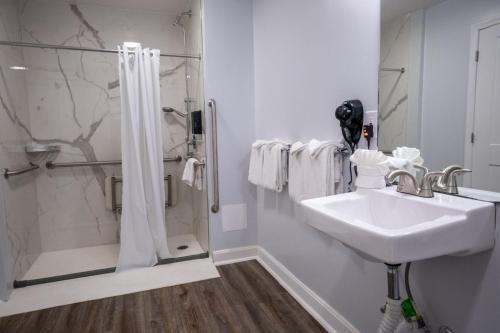 a white bathroom with a shower and a sink at Outer Banks Motor Lodge in Kill Devil Hills