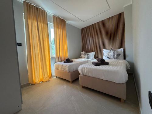 two beds in a room with yellow curtains at Exclusive Rooms in Jadranovo