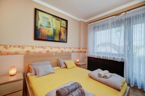 a bedroom with a yellow bed and a window at 6RoomS BALATON-HÉVÍZ in Hévíz