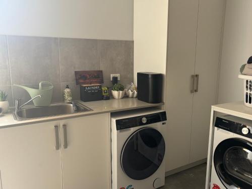 a kitchen with a washing machine and a sink at JettyWalk, Stunning 3br townhouse, walk to beach in Rosebud