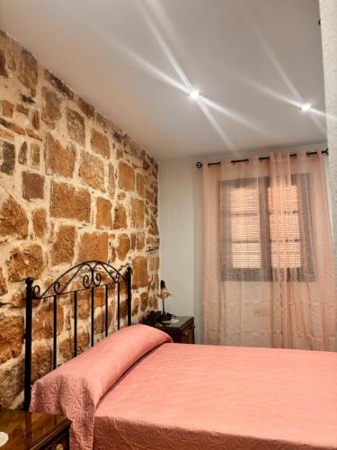 una camera da letto con un letto e un muro di pietra di La casa del castillo a Baños de la Encina