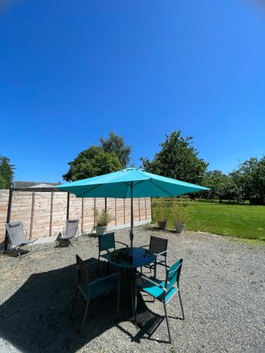 a table and chairs under a blue umbrella at Gîte à la campagne in Le Mesnil-Villeman