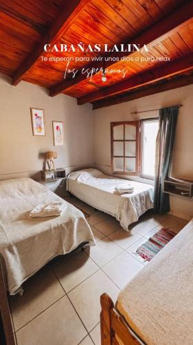 a bedroom with two beds and a wooden ceiling at Casa Lalina in Laprida
