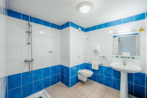 une salle de bain bleue et blanche avec des toilettes et un lavabo dans l'établissement Centre International de Sejour, à Fort-de-France