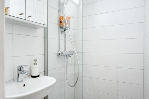 a white bathroom with a shower and a sink at SELF-SERVICE penthouse studio in the heart of Turku! in Turku