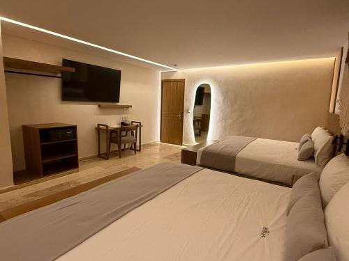 a hotel room with two beds and a flat screen tv at Hotel Makkan Boca in Veracruz