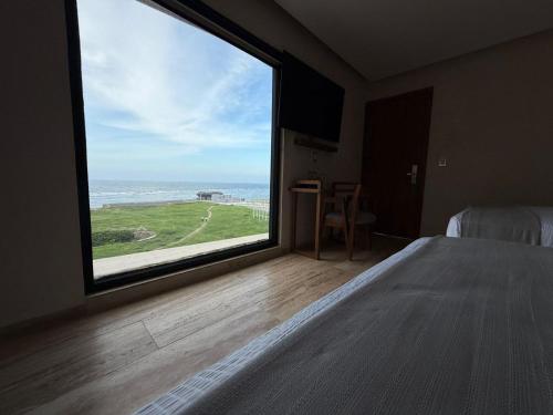 a bedroom with a large window with a view of the ocean at Hotel Makkan Boca in Veracruz