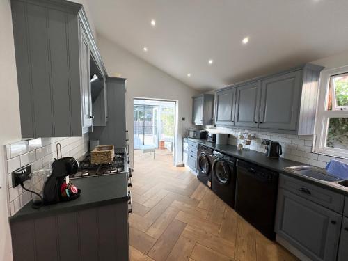 a kitchen with gray cabinets and a washer and dryer at QUEENS RETREAT- Luxe 3-Bed Comfort, Sleeps 6, PERMITTED PARKING FOR 2 CARS, Pet-friendly & close to bars and Restaurants in Lincoln