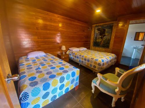 a bedroom with two beds and a chair in it at Casa Real - Oxapampa BnB in Oxapampa