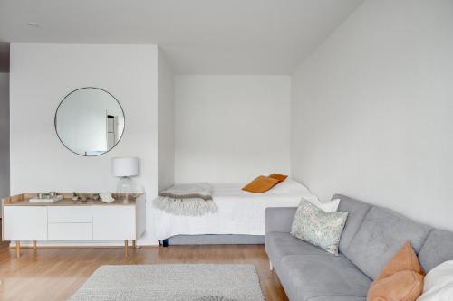 a living room with a couch and a mirror at SELF-SERVICE penthouse studio in the heart of Turku! in Turku
